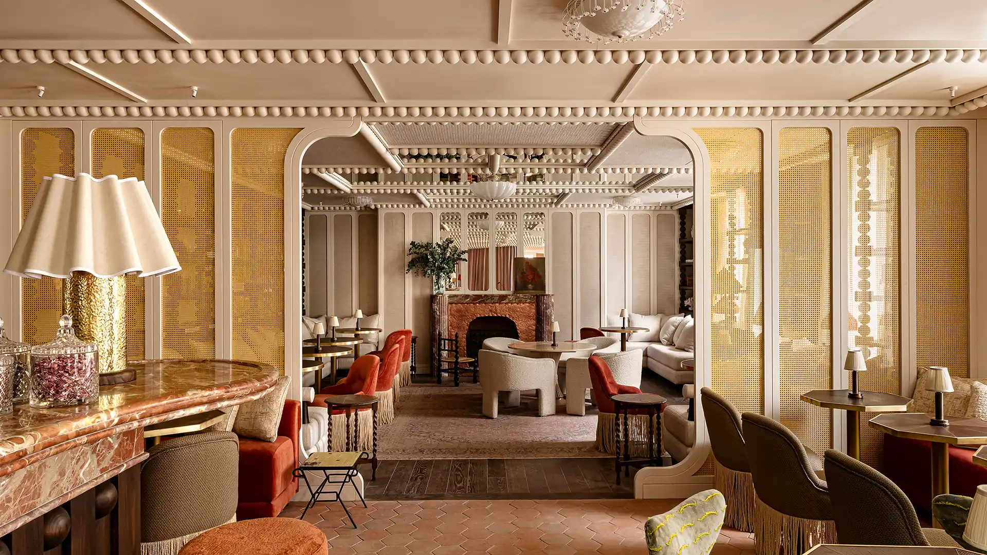 Salon lounge vue depuis le bar avec cheminée fauteuils bouclette et velours terracotta Château des Fleurs