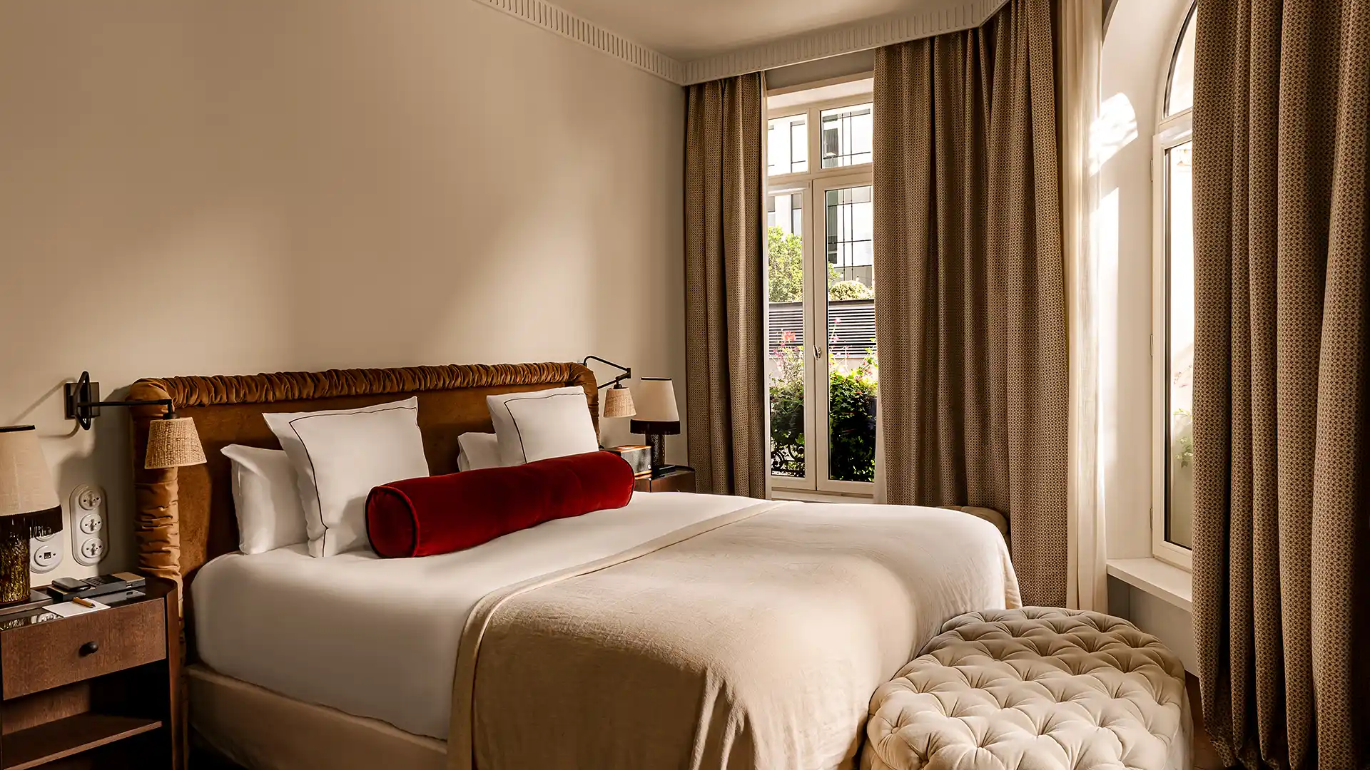 Chambre lumineuse avec lit double coussin bolster rouge tête de lit capitonnée et fenêtre donnant sur balcon Château des Fleurs