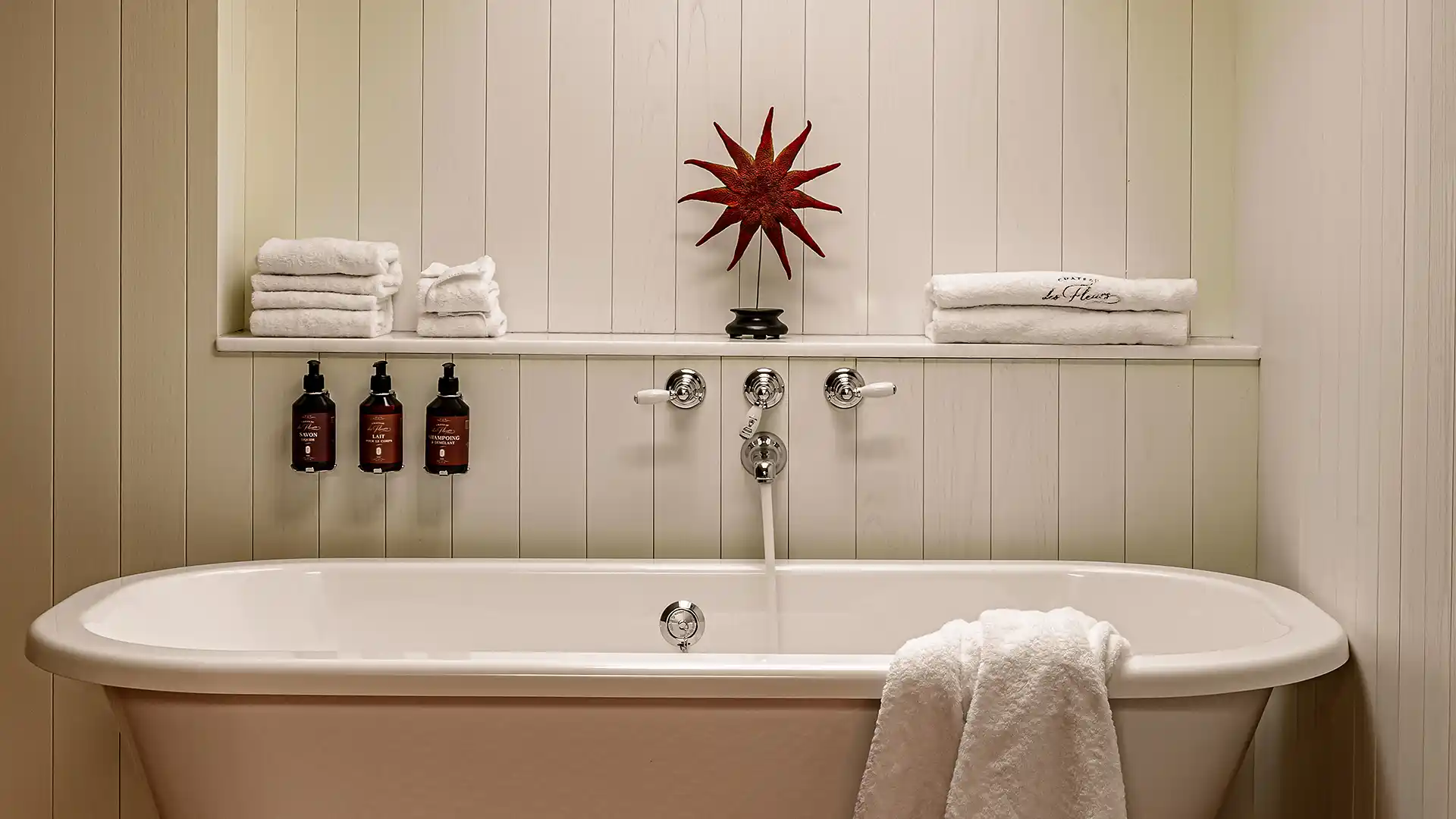 Baignoire îlot avec robinetterie chromée serviettes pliées et produits de bain Château des Fleurs