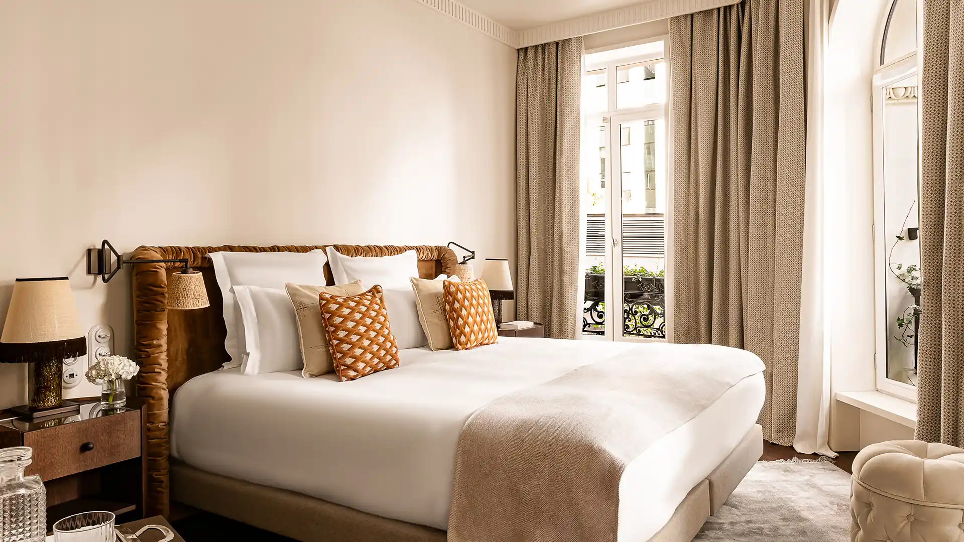 Chambre lumineuse avec lit king size coussins motif géométrique orange et fenêtre balcon Château des Fleurs