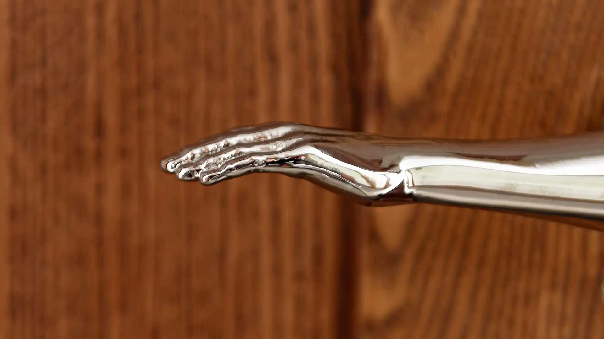 Poignée de couvert en argent sculptée en forme de main sur fond de bois