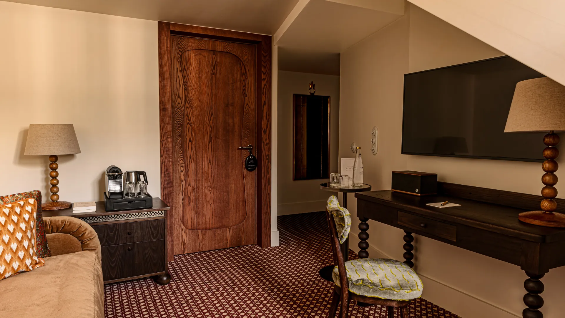 Salon cosy aux tons bois foncé et velours moutarde avec tapis à motifs Château des Fleurs