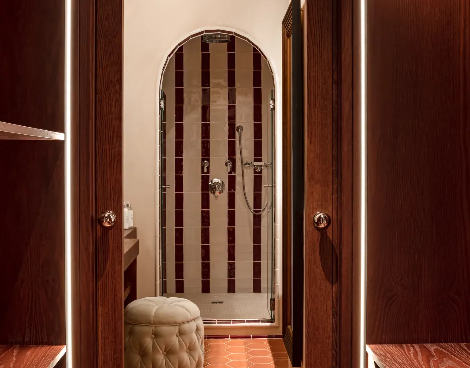 Douche voûtée avec carrelage rayé rouge et blanc pommeau de pluie et pouf capitonné Château des Fleurs