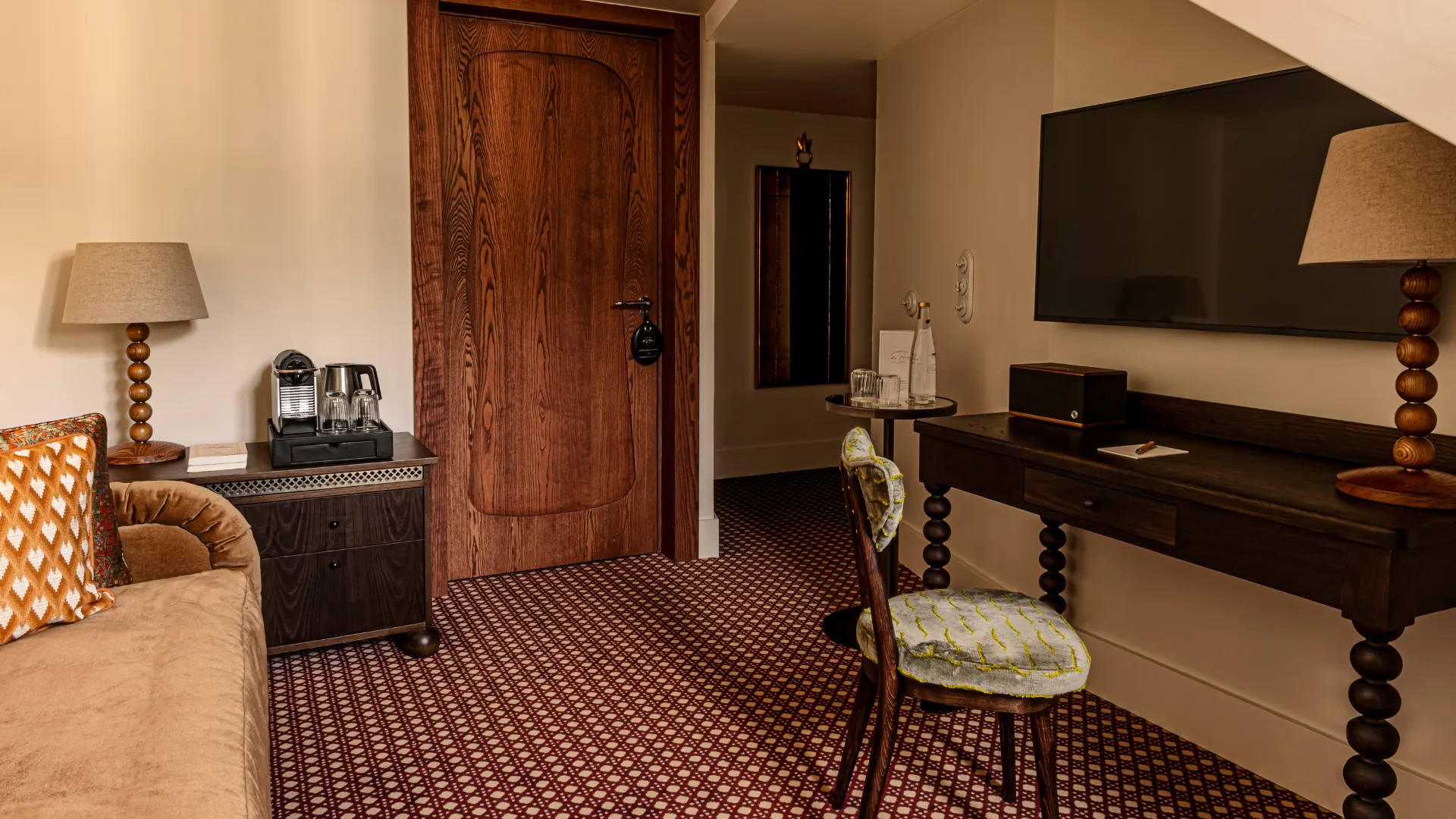 Salon cosy aux tons bois foncé et velours moutarde avec tapis à motifs Château des Fleurs