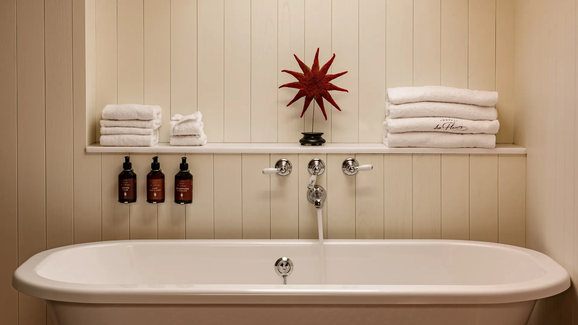 Baignoire sur pieds avec serviettes pliées produits de bain et étoile décorative rouge Château des Fleurs