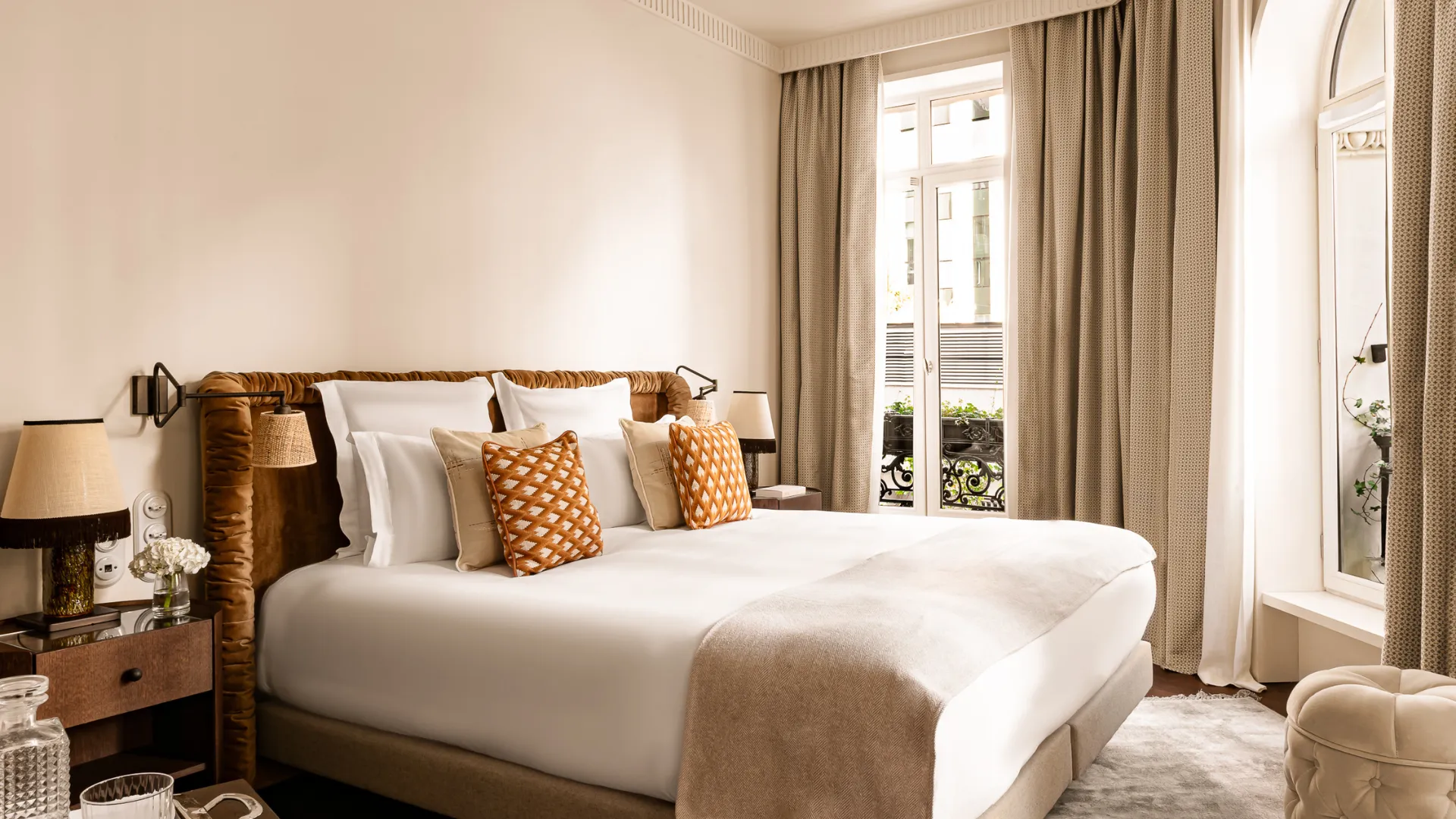 Chambre spacieuse avec lit tête de lit velours coussins orange et fenêtre donnant sur cour intérieure Château des Fleurs