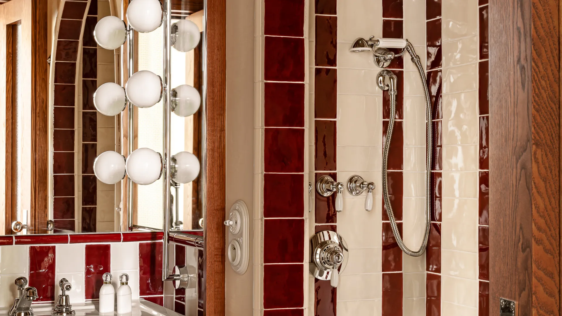 Casa de banho retro com azulejos às riscas vermelhos e brancos, espelho iluminado e duche abobadado – Château des Fleurs
