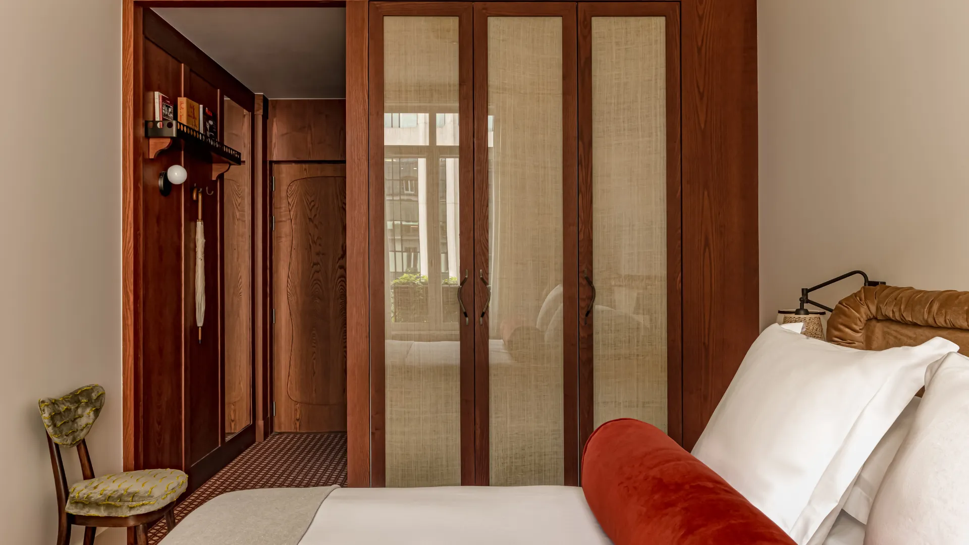 Chambre avec armoire en bois à panneaux tressés porte-parapluie et lit velours coussin rouge Château des Fleurs