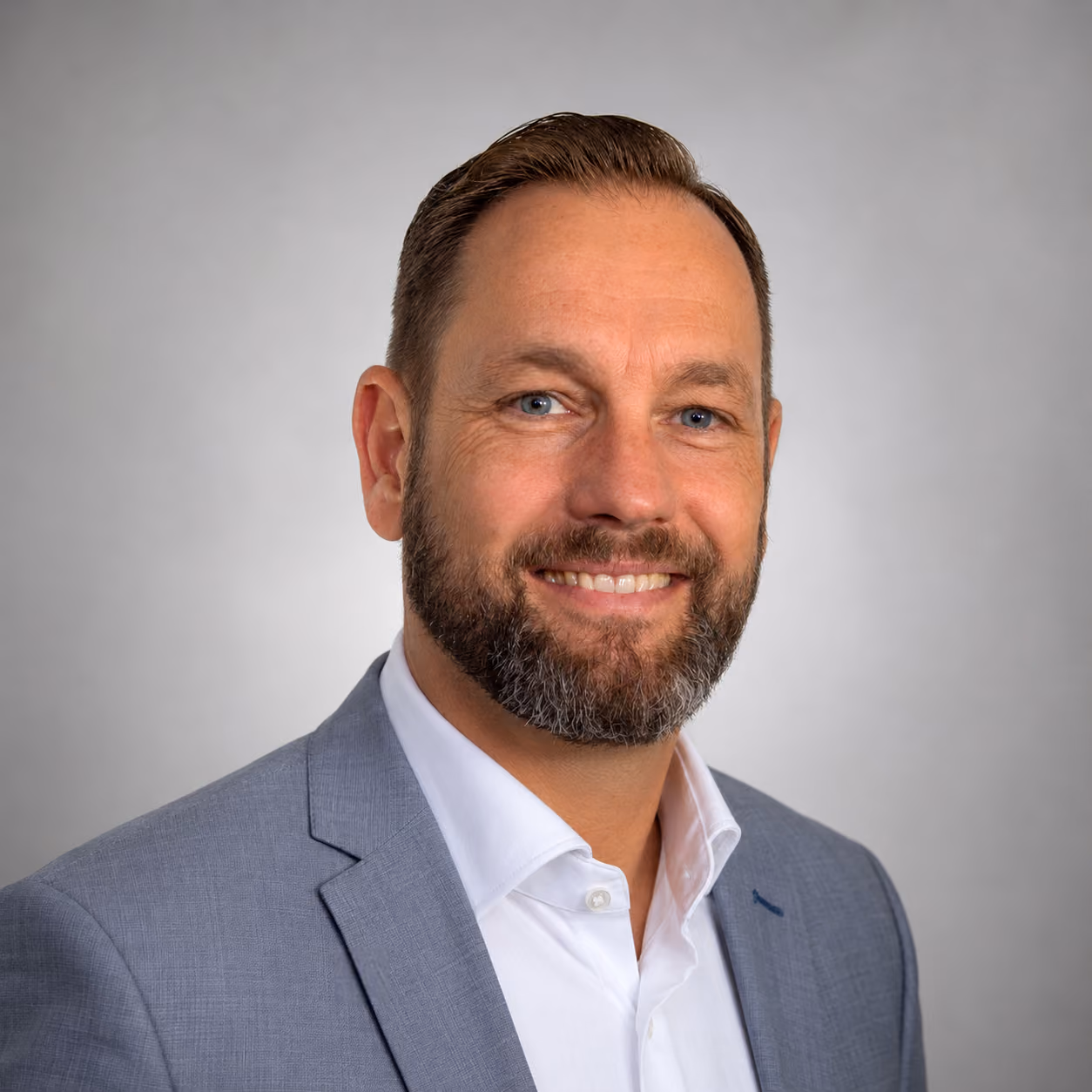 Smiling man with beard wearing a light blue Inmark Life Science shirt against a plain background.