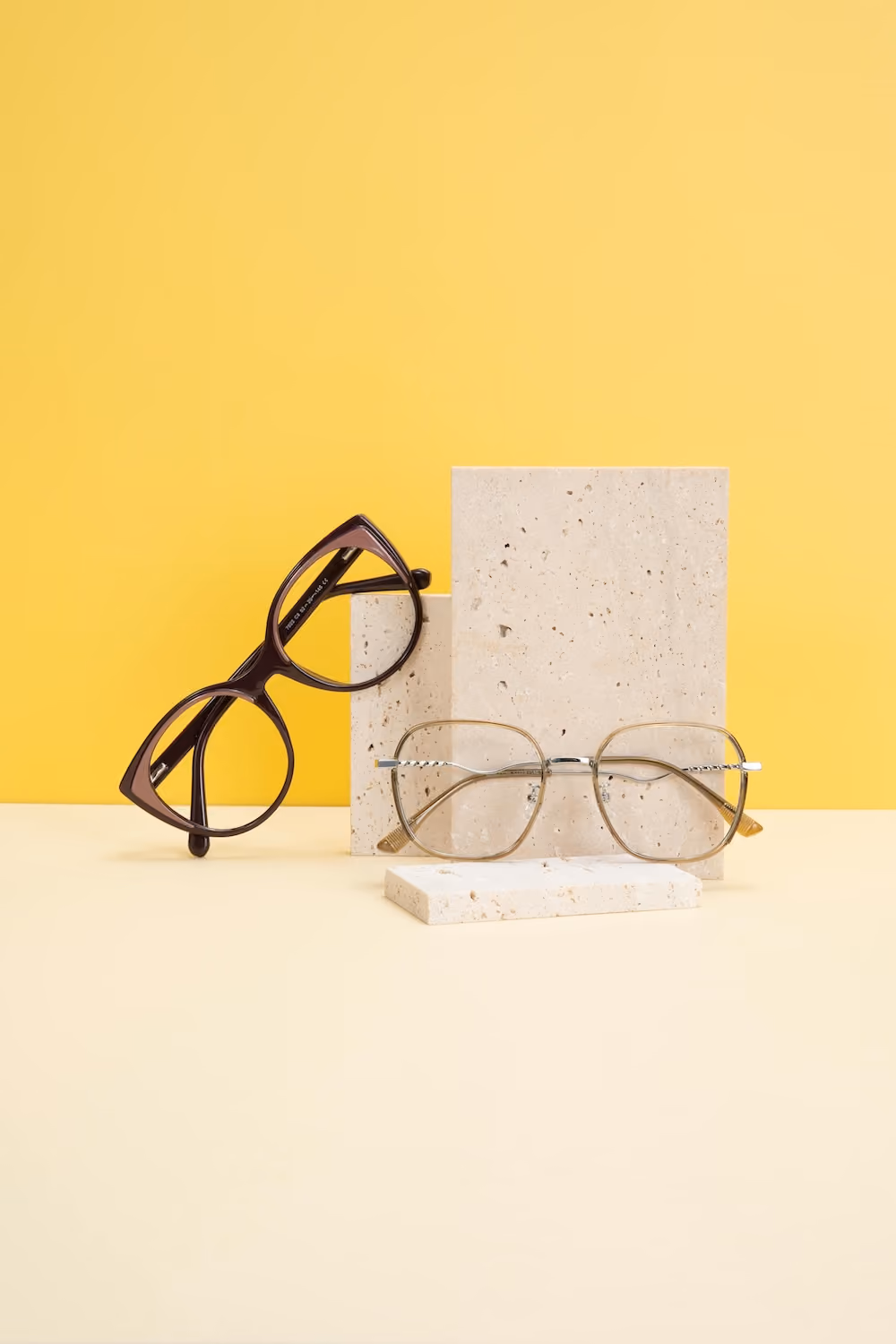 A pair of glasses and a paper are placed against yellow background with white edges.