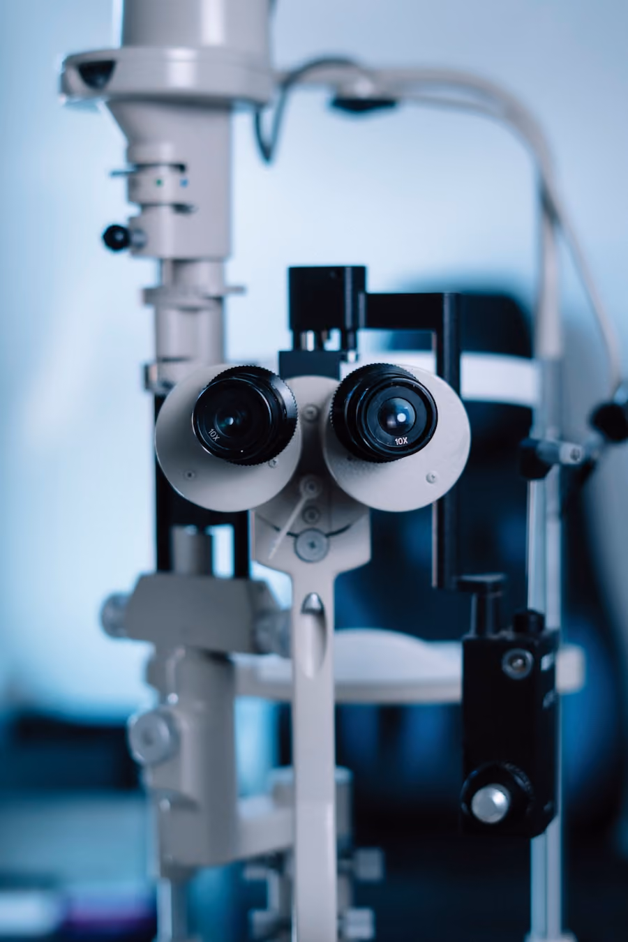 A microscope with two lenses and a camera attachment is shown through a blue-tinted glass.