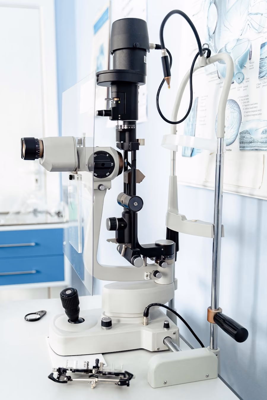 A microscope with a black and white cord is placed on top of a table.