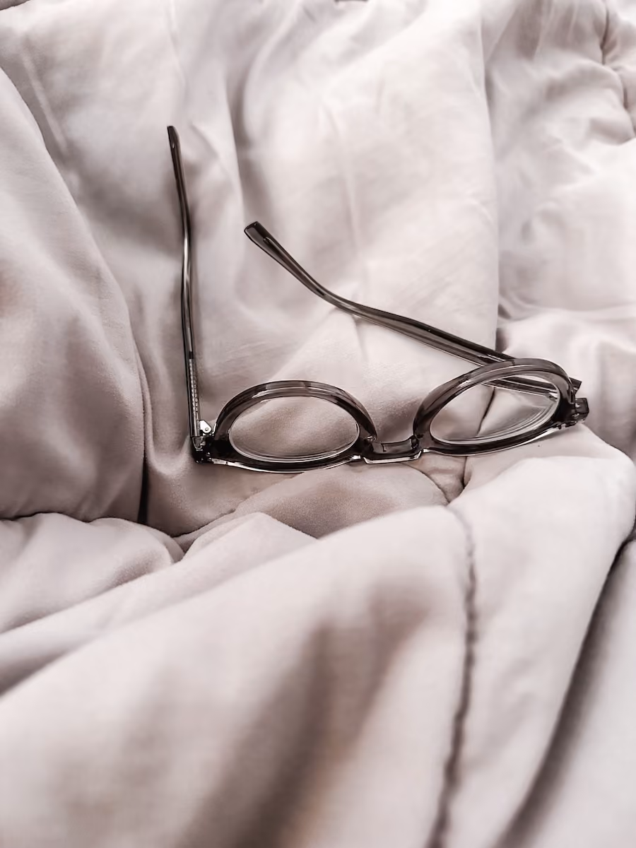 Glasses on an gray white pillow blanket