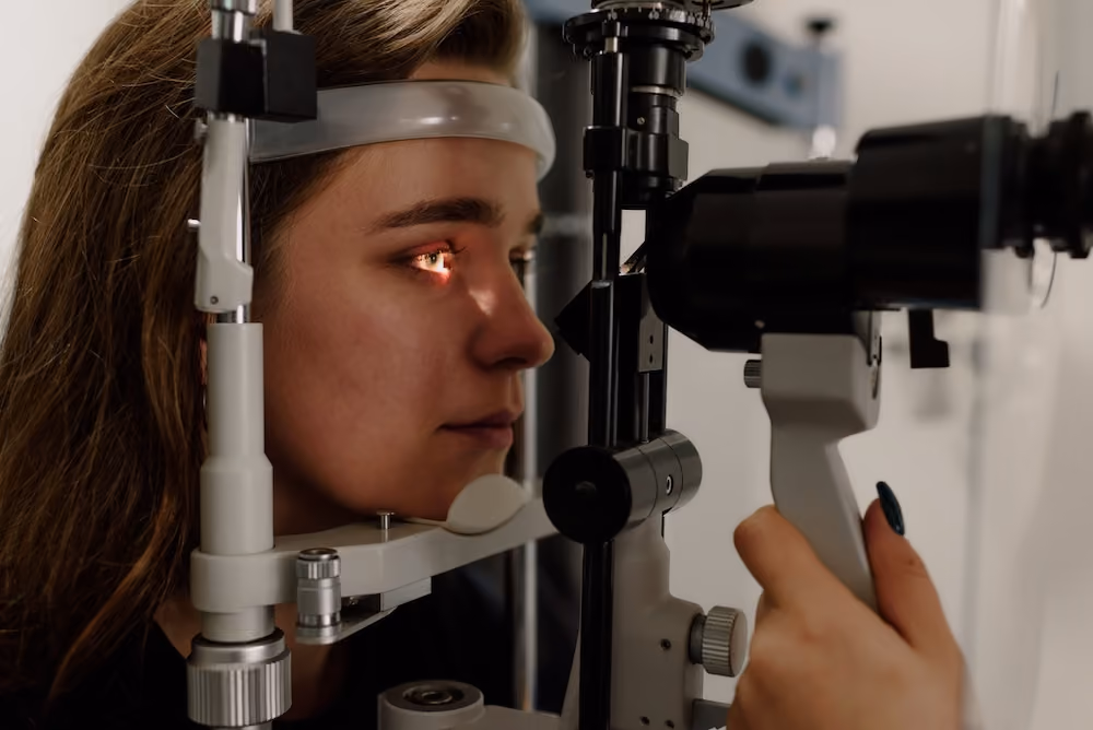A person is looking through an eye test machine with a headband and lights on their face.
