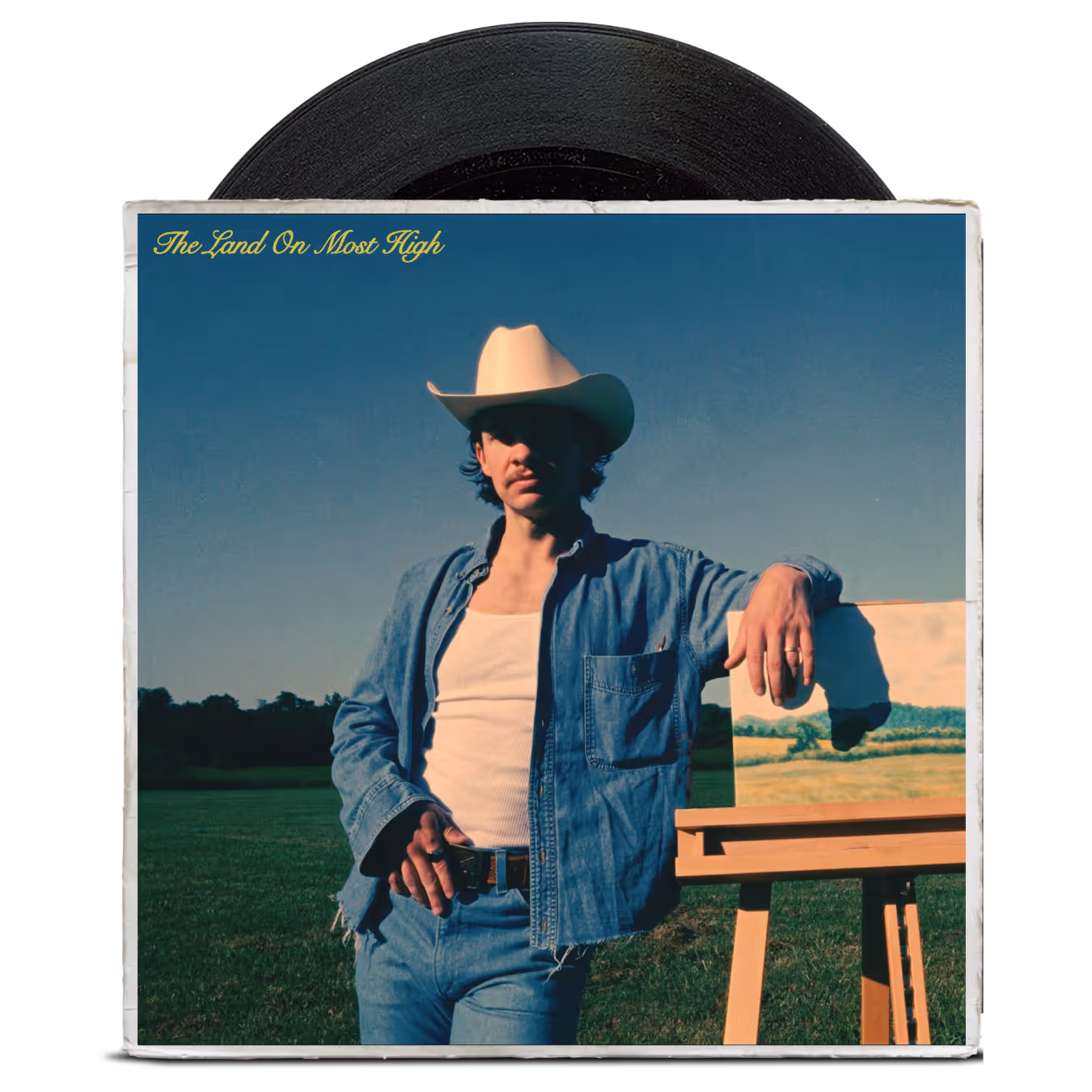 Man in white cowboy hat and denim jacket leaning on easel with landscape painting outdoors under clear sky.