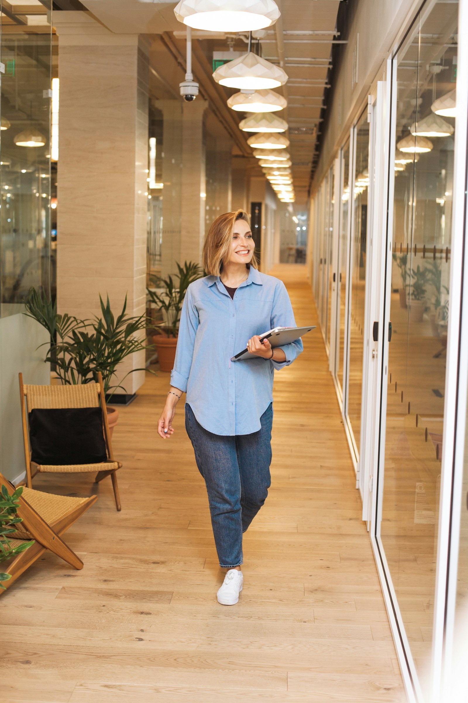 Mulher lider católica caminhando em corredor iluminado, representando liderança e fé no ambiente profissional