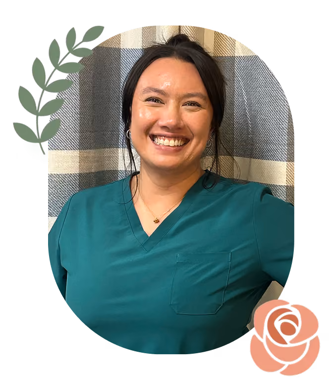 Smiling woman in teal scrubs stands against a plaid backdrop with leaf and rose graphics.