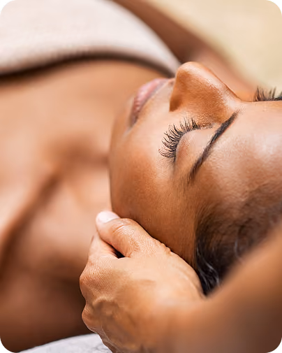 Close-up of a woman receiving a gentle head massage with eyes closed, relaxing.