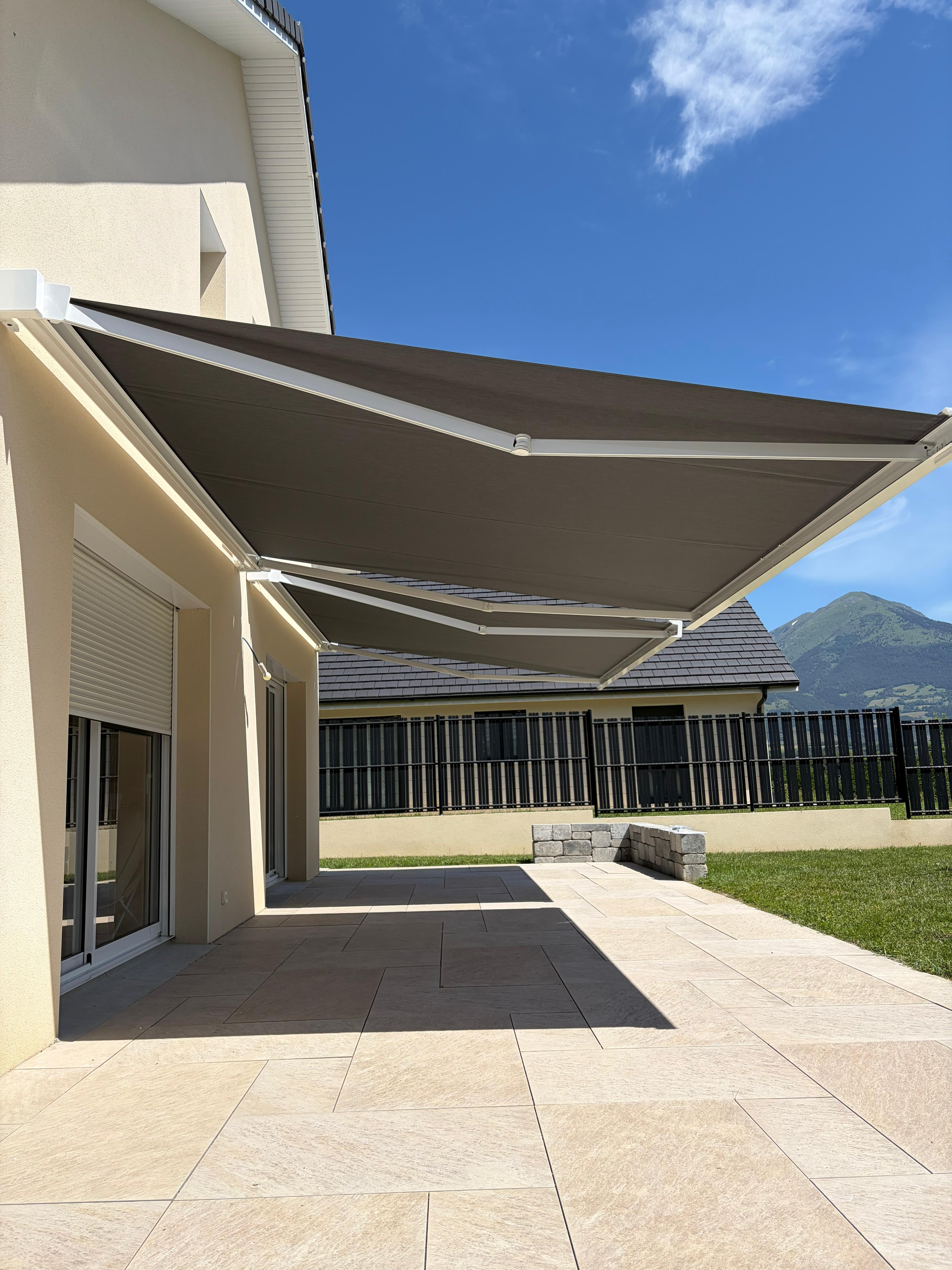 Entrée d'une maison moderne avec portillon en métal noir et chemin pavé sur herbe verte.