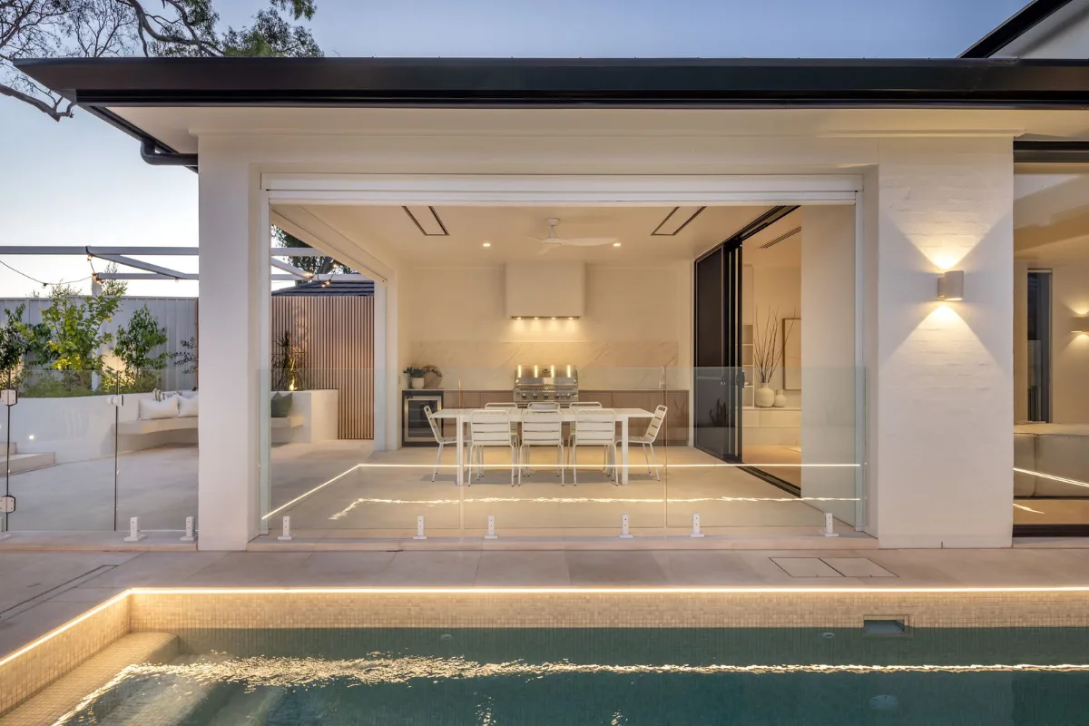 Covered alfresco dining pavilion opening to the pool at dusk at 9 Netherby