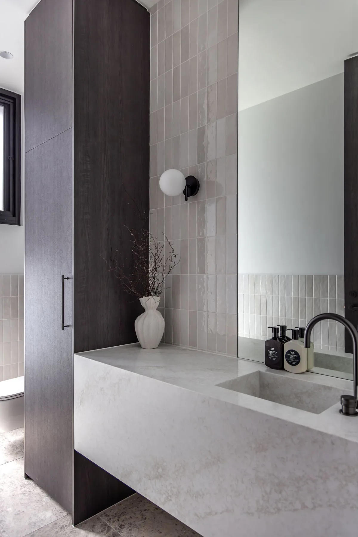 Cantilevered stone vanity with black tapware and glazed tiles in a bathroom at 9 Netherby