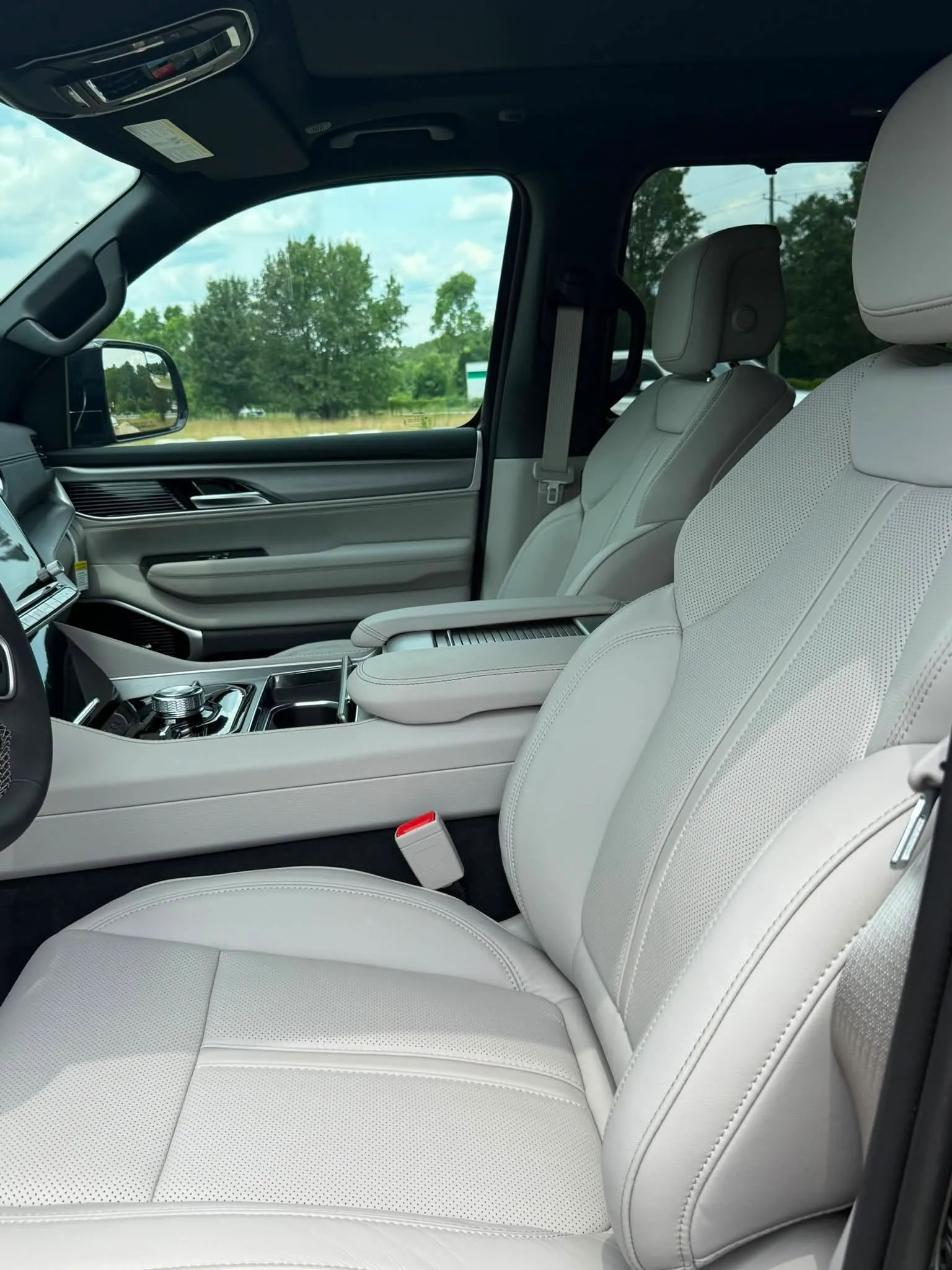 Front seats of a Jeep Grand Wagoneer with light gray leather upholstery and center console controls.