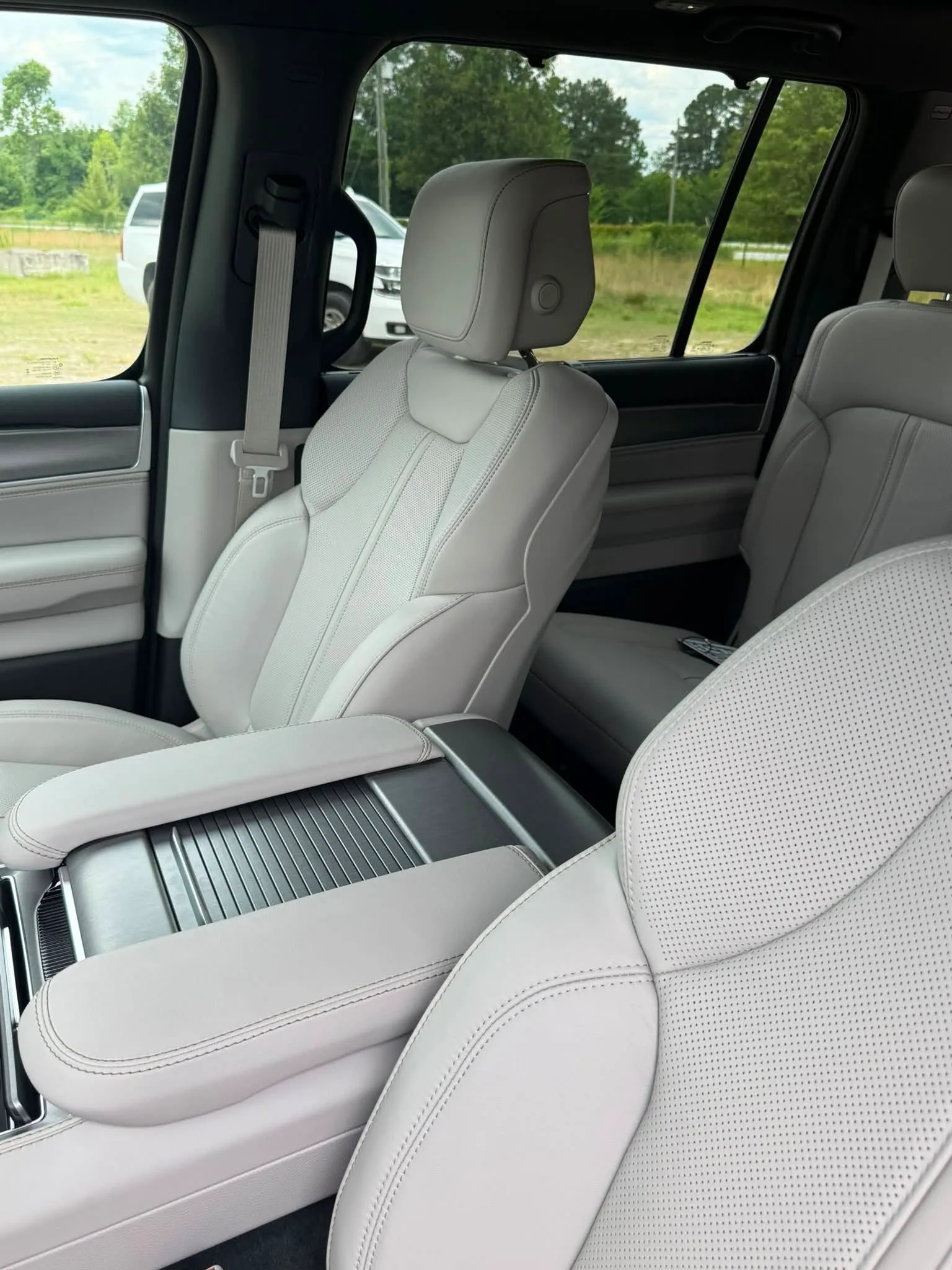 Light gray leather Jeep Grand Wagoneer interior with front bucket seats and a center console compartment.