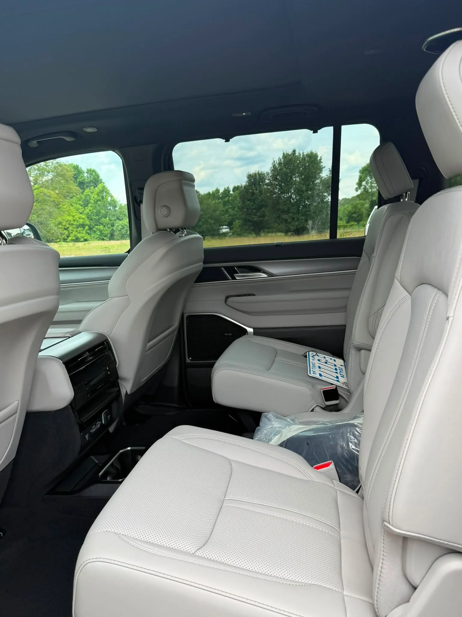 Interior of a Jeep Grand Wagoneer showing two rows of light gray leather seats.