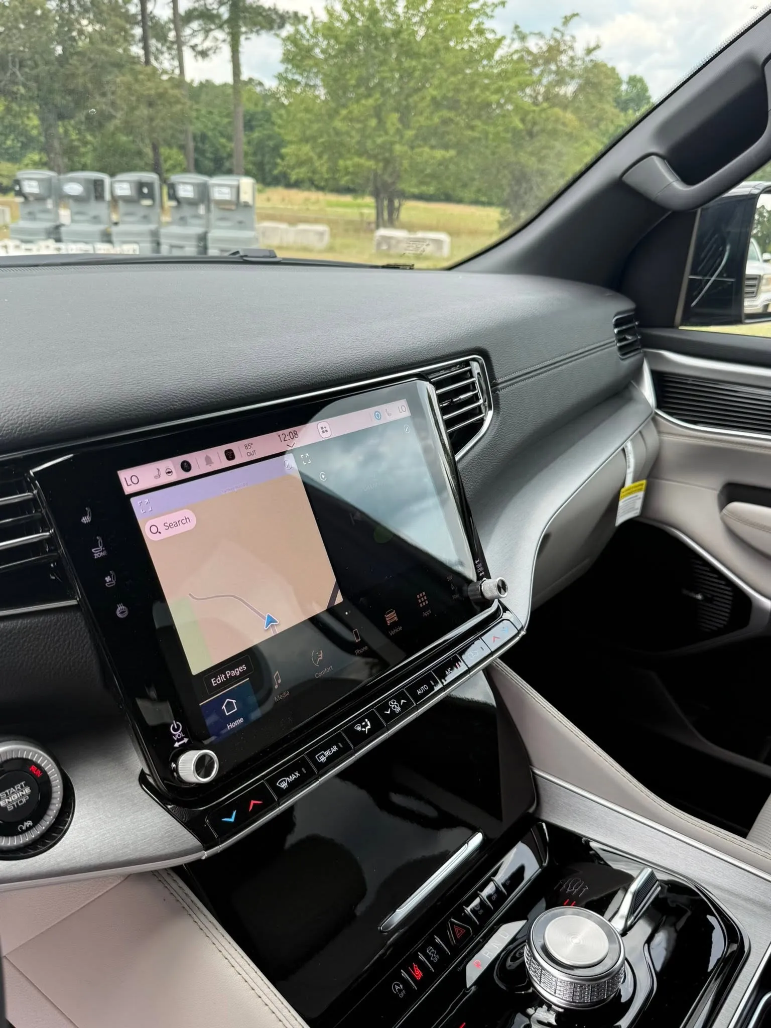 Jeep Grand Wagoneer interior showing dashboard with touchscreen navigation and center console with control dial and buttons.