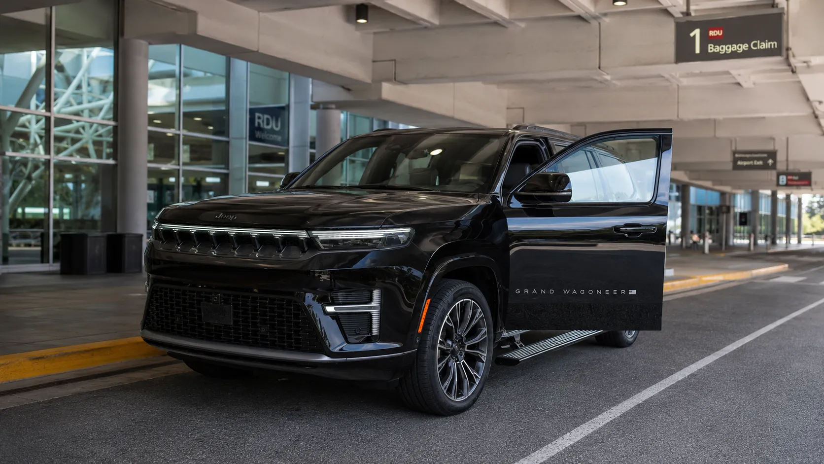 RM Executive's Black Jeep Grand Wagoneer SUV with driver door open parked outside of Raleigh-Durham International Airport baggage claim area.