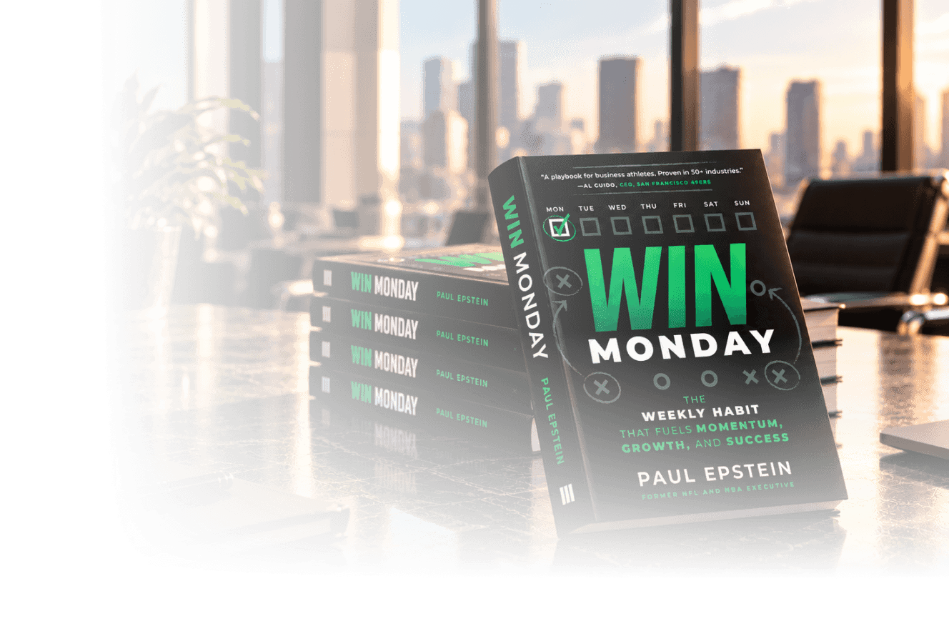 Stack of books titled 'Win Monday' by Paul Epstein displayed on a table in a modern office with cityscape view through large windows.