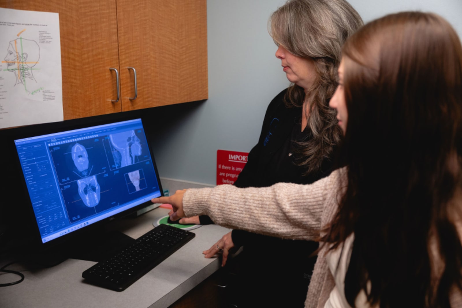Craniofacial specialist pointing to imaging on computer screen during consultation