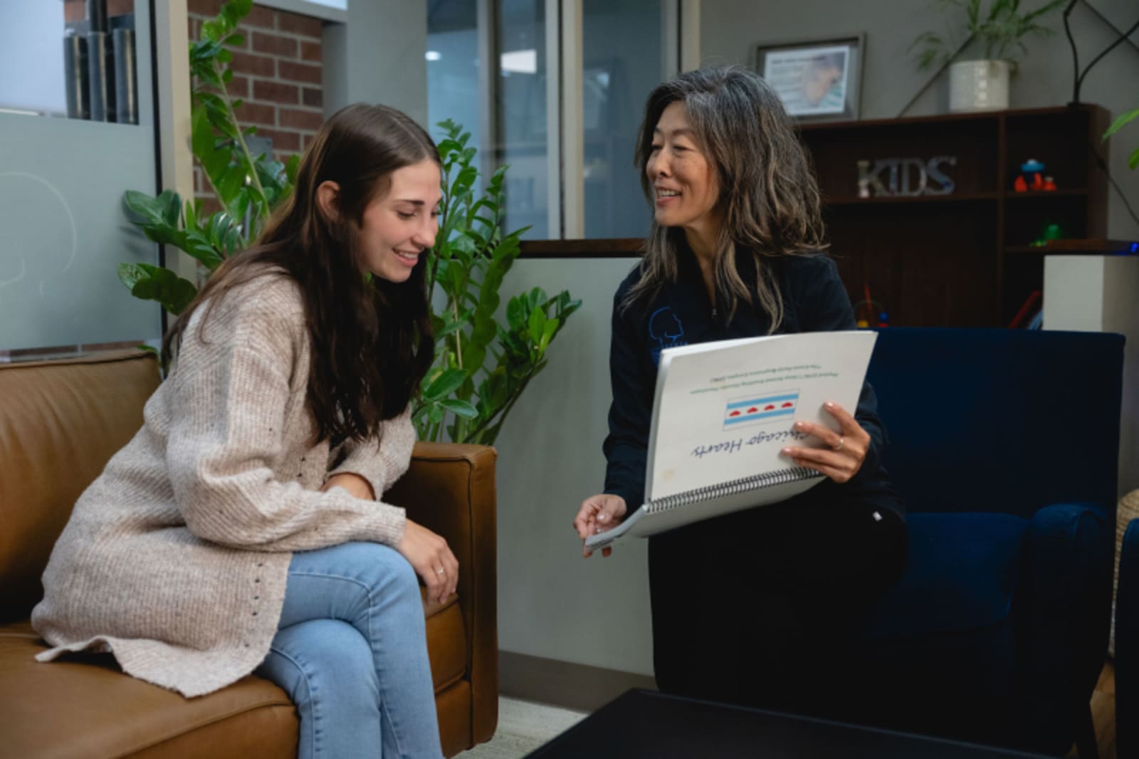 A dental provider discusses treatment options with a patient holding a document in a modern office setting.