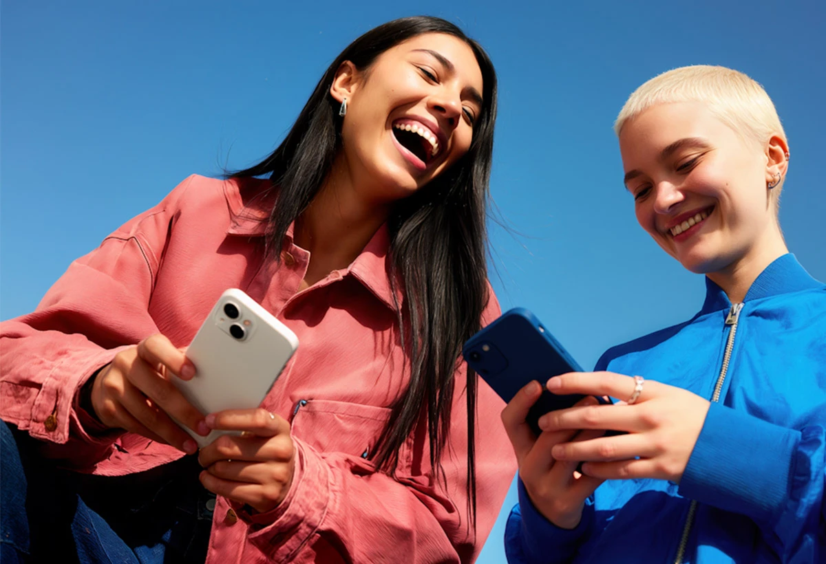 Two people smiling while holding smartphone in colorful studio setting