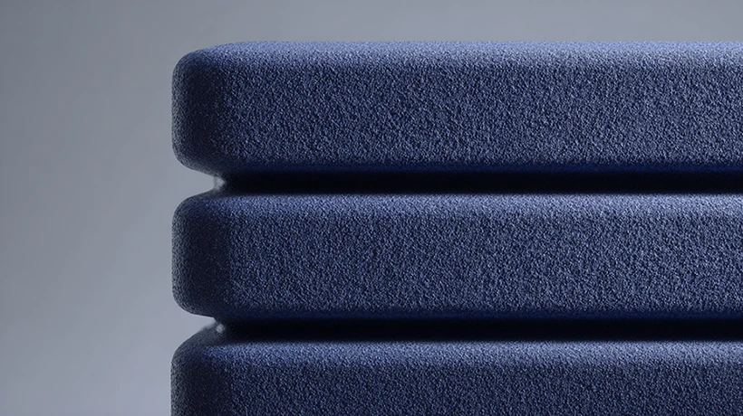 Close-up of three stacked blue foam cushions with a textured surface outdoors.