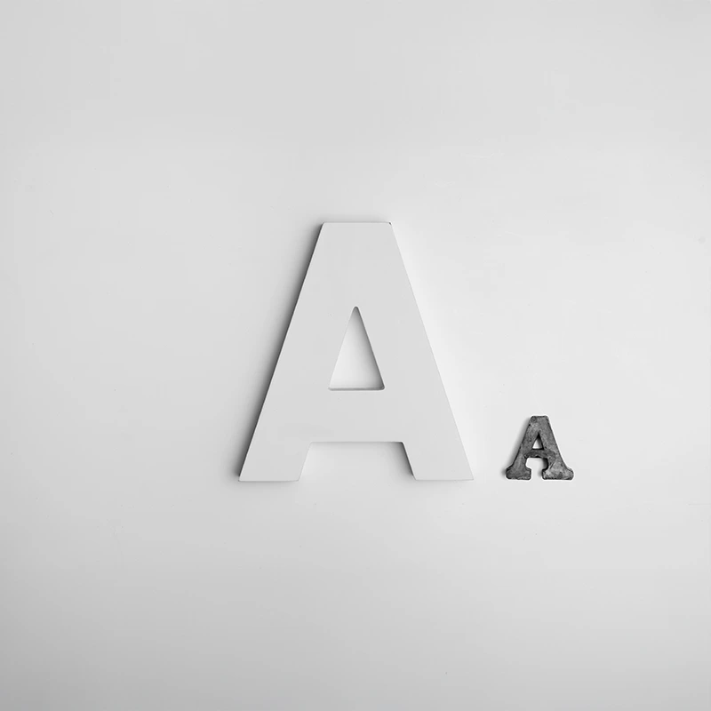 Large white letter A next to a small metallic letter A on a plain gray background.