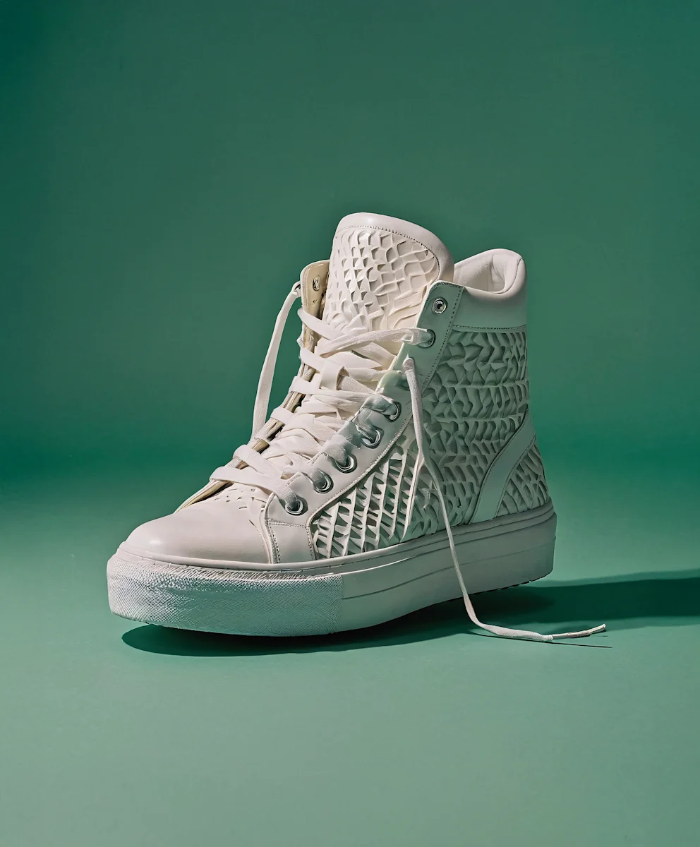 White high-top sneaker with textured geometric pattern on a green background.