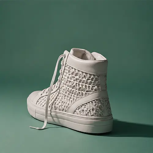 White high-top sneaker with textured geometric pattern on a green background.