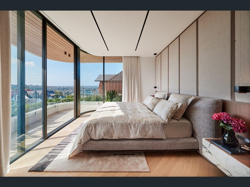 Master bedroom with curved floor-to-ceiling glazing and harbour outlook