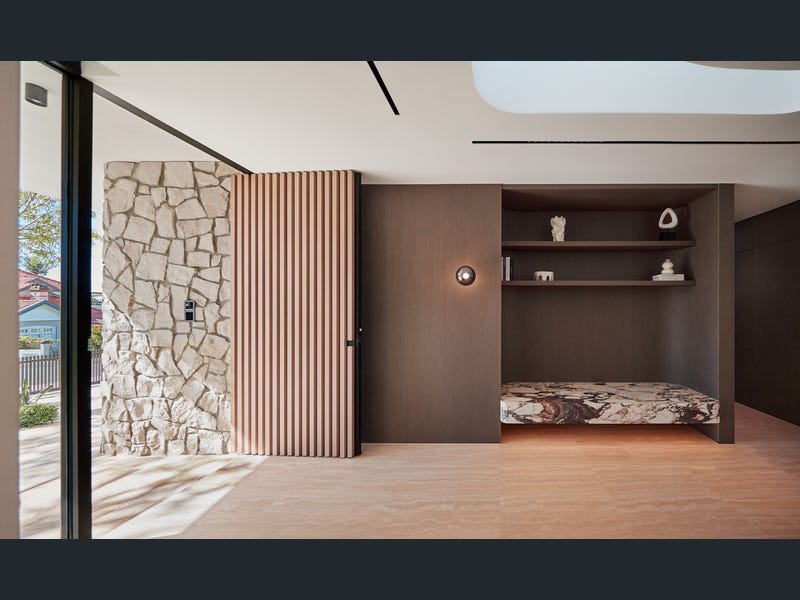 Entry hall — sandstone wall, timber batten pivot door and marble bench