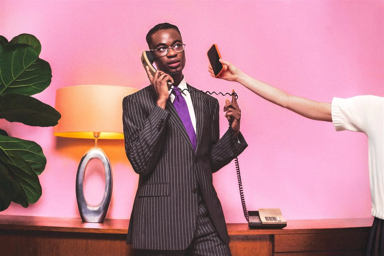 Homme en costume rayé téléphonant avec un combiné, une main lui tendant un smartphone orange