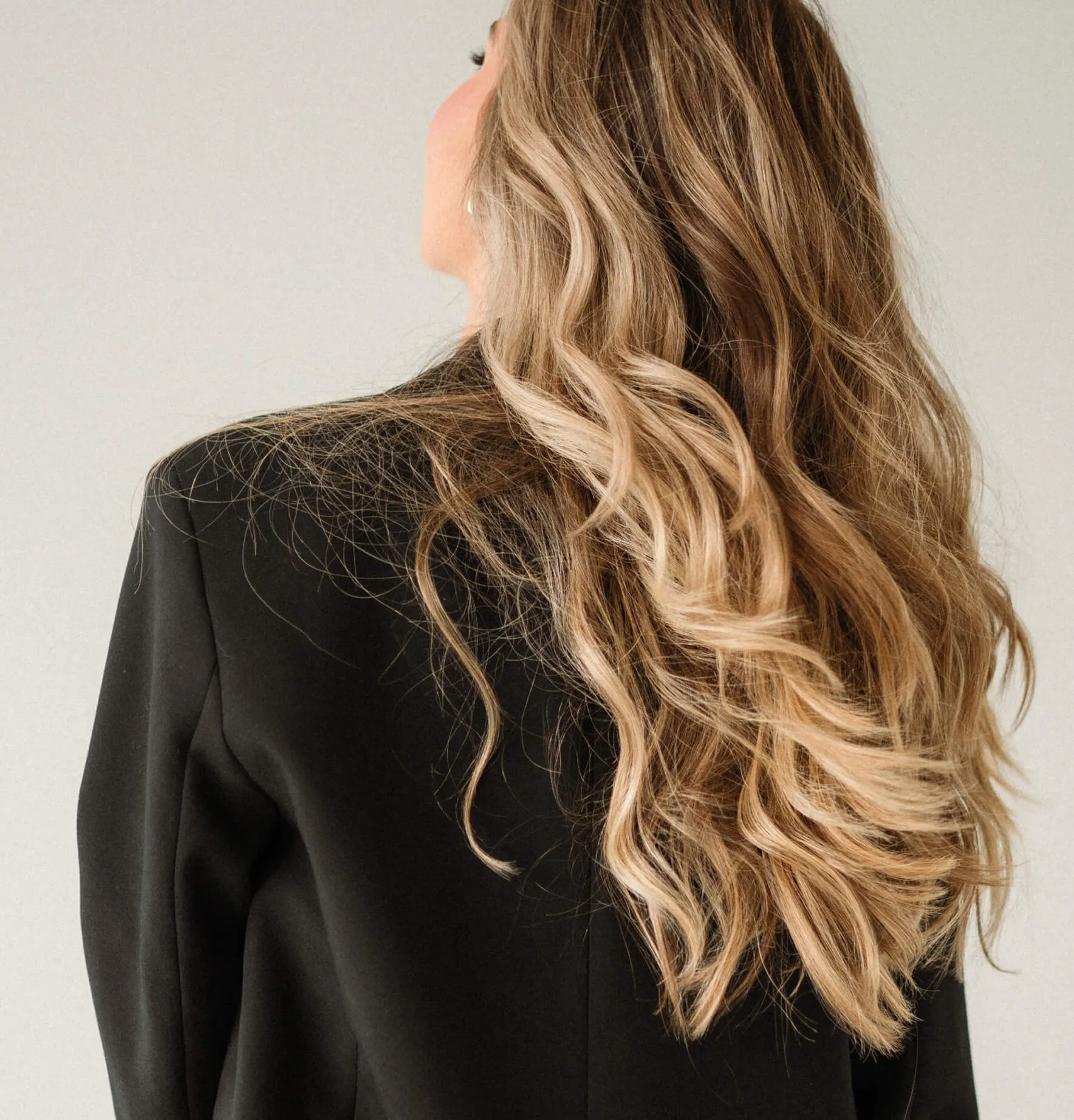 Back view of long lived-in blonde hair with soft balayage dimension and seamless blending.