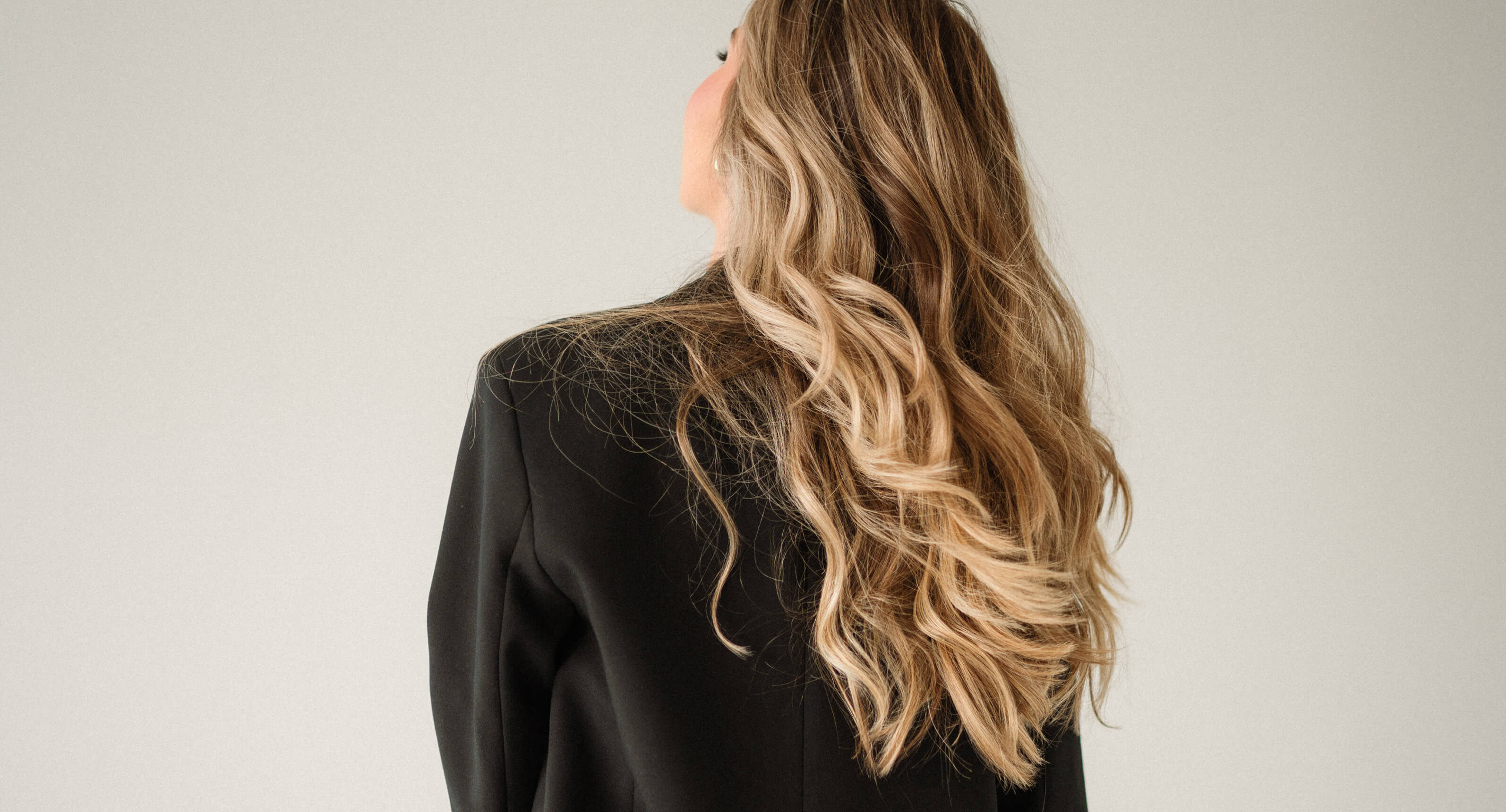 Back view of long lived-in blonde hair with soft balayage dimension and seamless blending done by SWOON by Kim Cimillo, a hair salon in West Caldwell, NJ