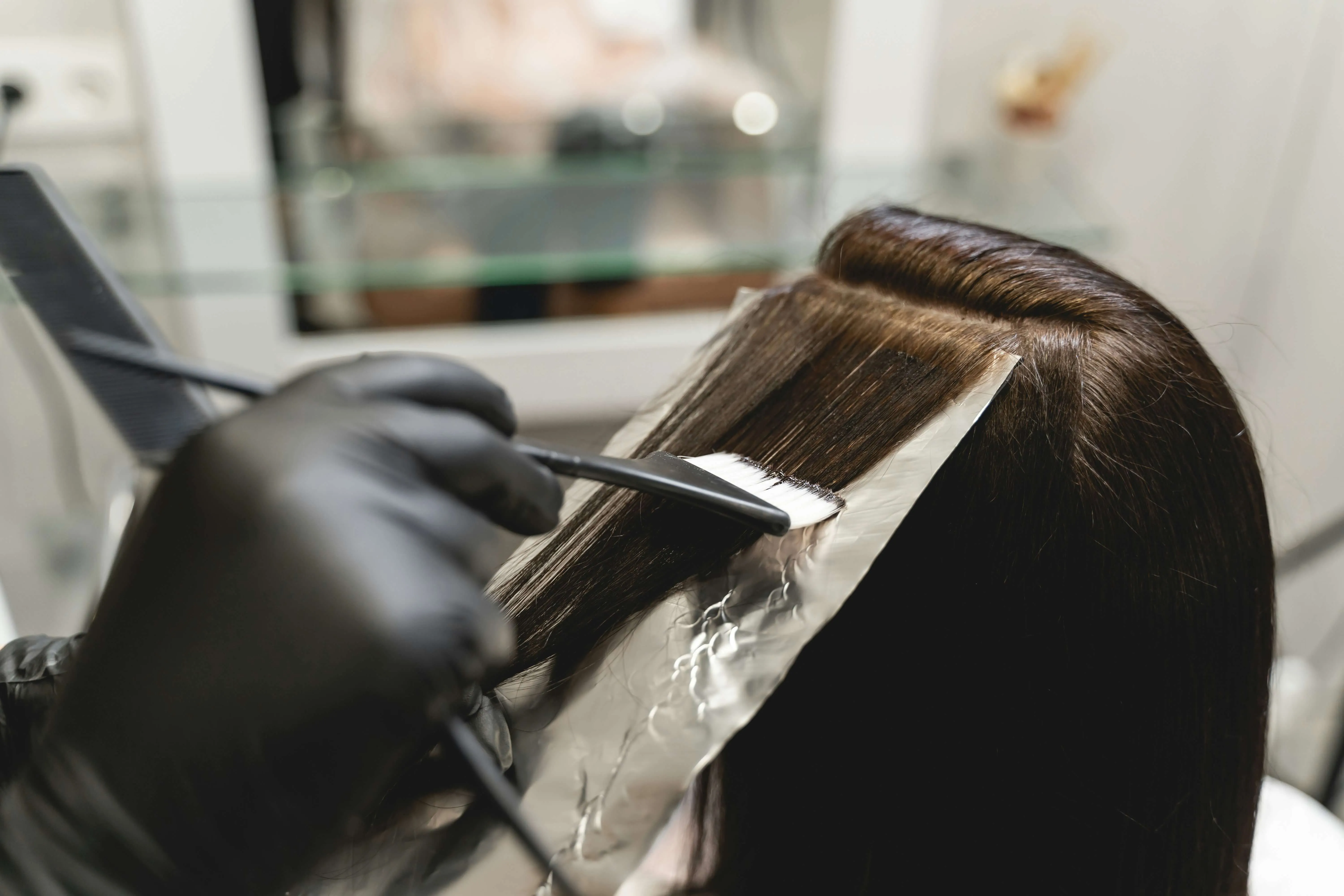 Stylist applying foil highlights during a professional hair coloring appointment.