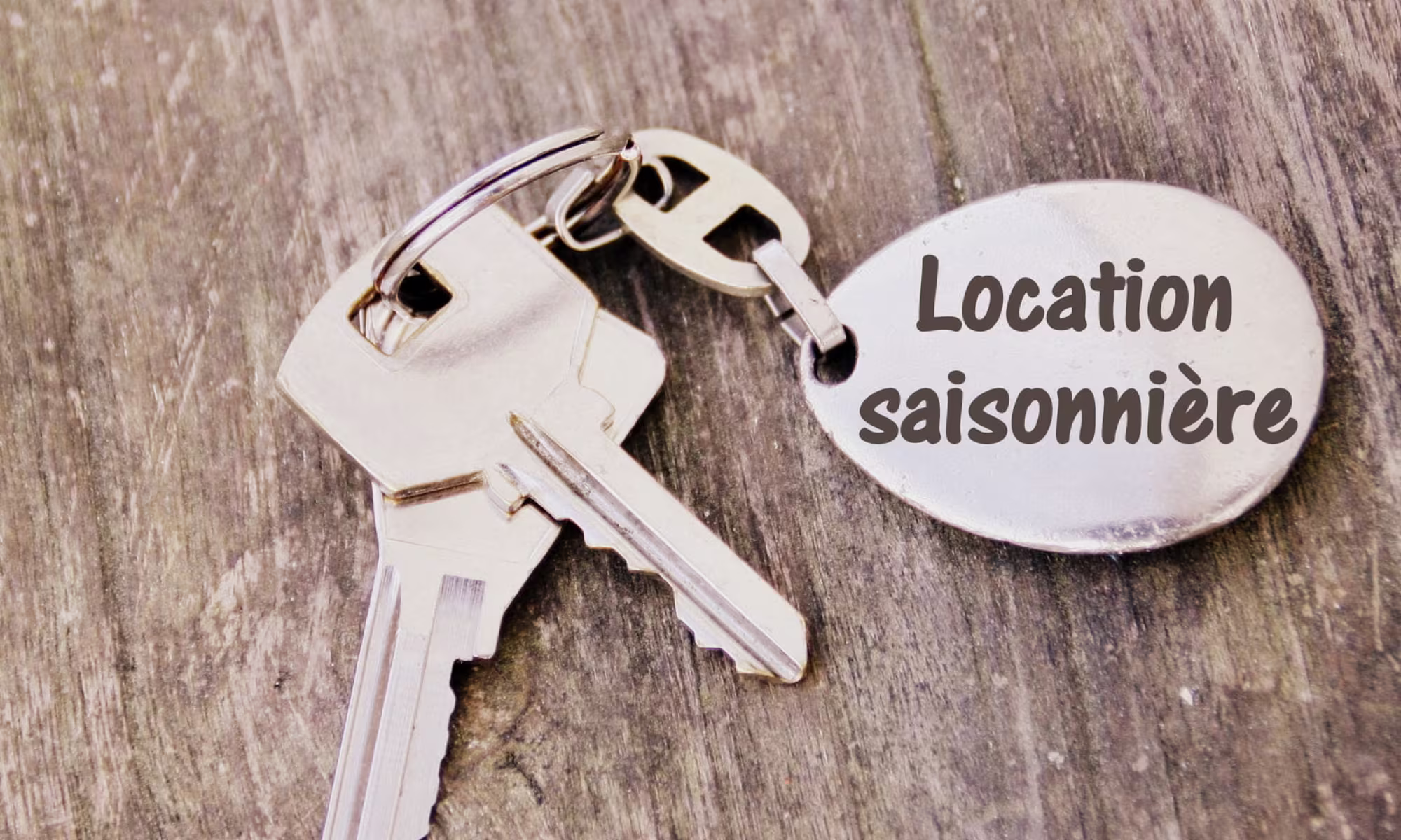 Trousseau de clés avec porte-clés « Location saisonnière » sur une table en bois