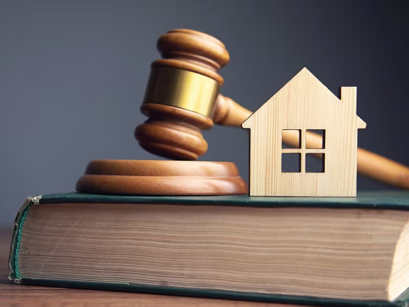Mazo de juez y casa de madera sobre un libro