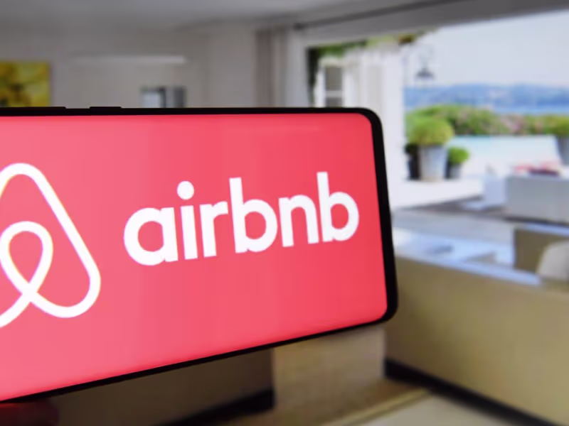 Smartphone con el logo de Airbnb en un salón con vista al mar