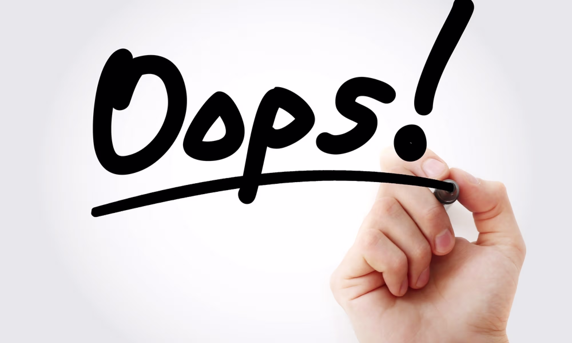 Mano escribiendo «Oops!» con un rotulador negro