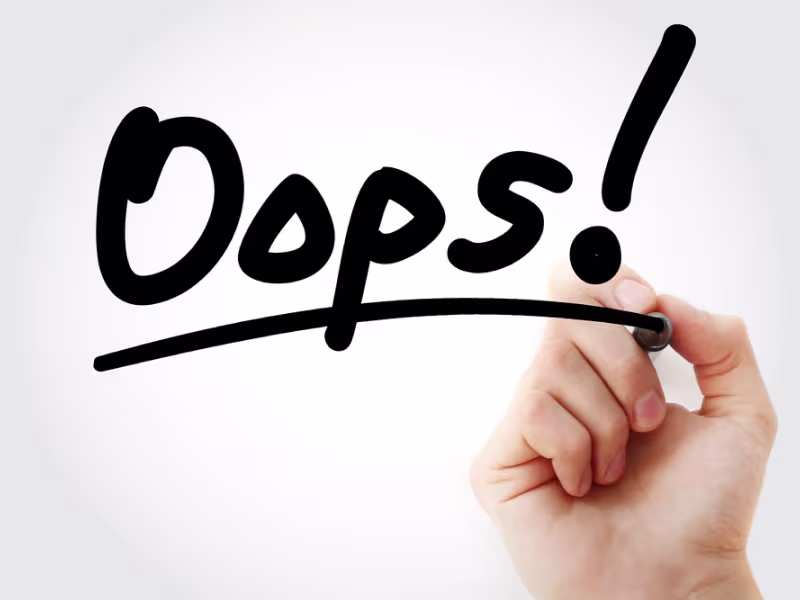 Mano escribiendo «Oops!» con un rotulador negro