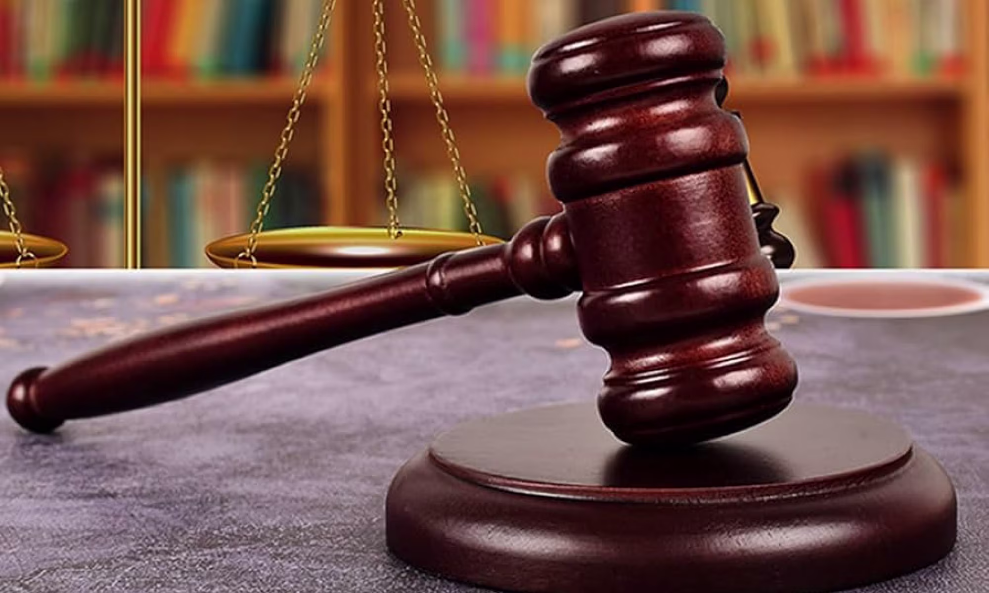 Mazo de juez y balanza de la justicia ante una estantería